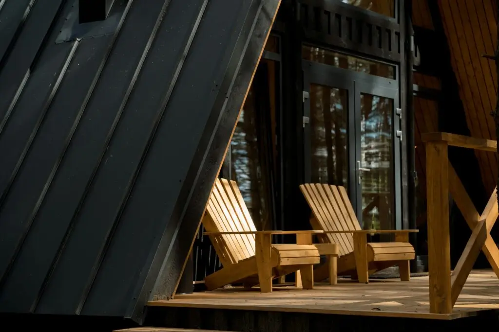 A peaceful wooden cabin porch featuring comfortable Adirondack chairs under warm sunlight.
